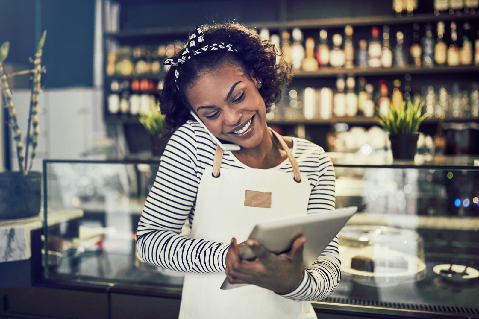 Smiling shop owner checking orders on a tablet