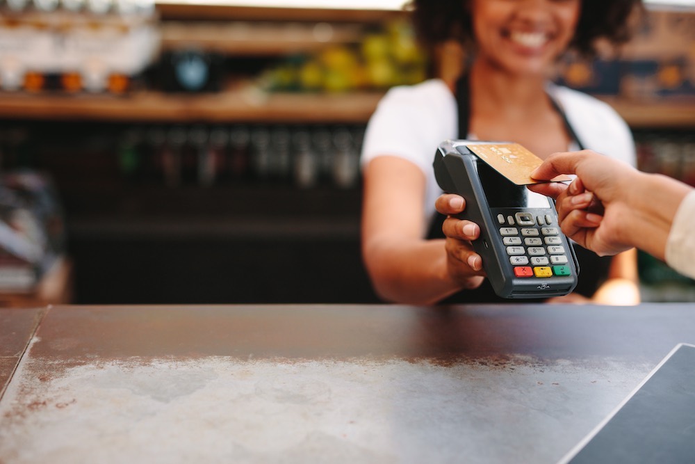 Smiling cashier taking a card payment at the counter
